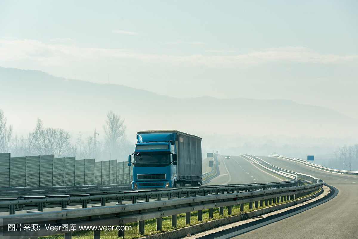 藍色的卡車在瀝青公路上行駛在鄉間的風景中